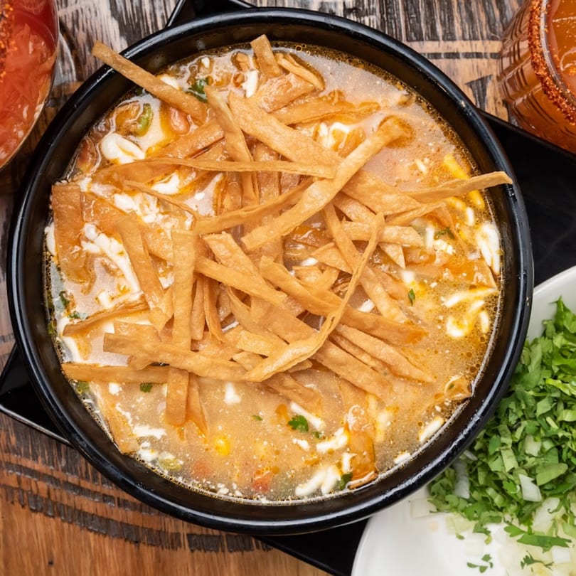 Habaneros Fresh Mexican Grill's tortilla soup, topped with crispy tortilla strips and a creamy drizzle.