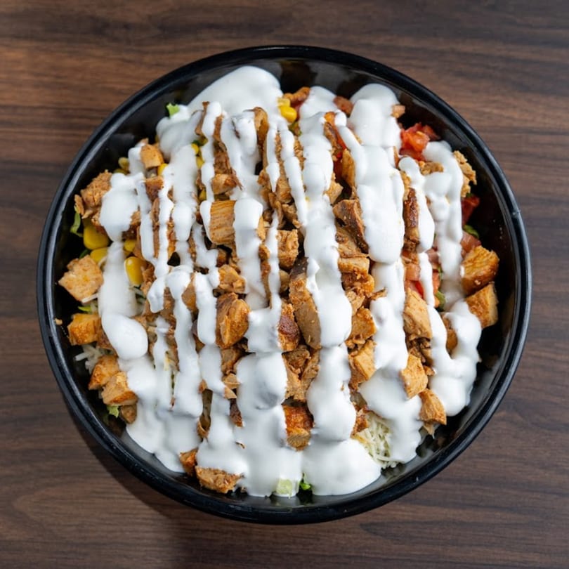 Habaneros Fresh Mexican Grill's chicken bowl, topped with white sauce, corn, and diced tomatoes.