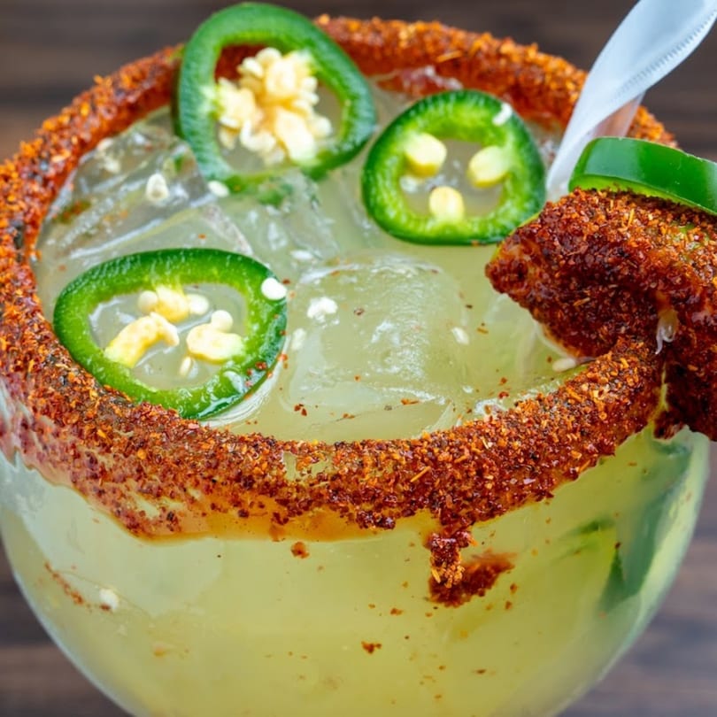 Spicy margarita with a chili-lime rim, fresh jalapeño slices, and a straw from Habaneros Fresh Mexican Grill.